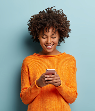 Satisfied hipster girl with afro haircut types text message cell phone enjoys online communicatio